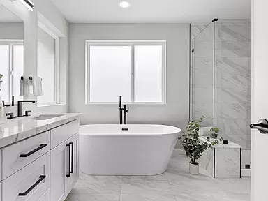 Modern bathroom with white tub, marble tile, and glass shower.