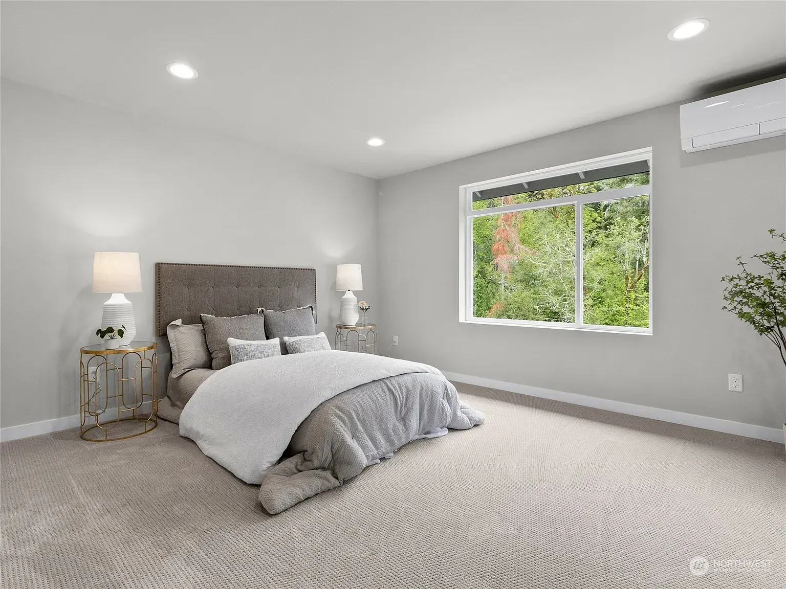 Bedroom with a bed, two nightstands, and a window overlooking greenery. Light gray walls, carpet.