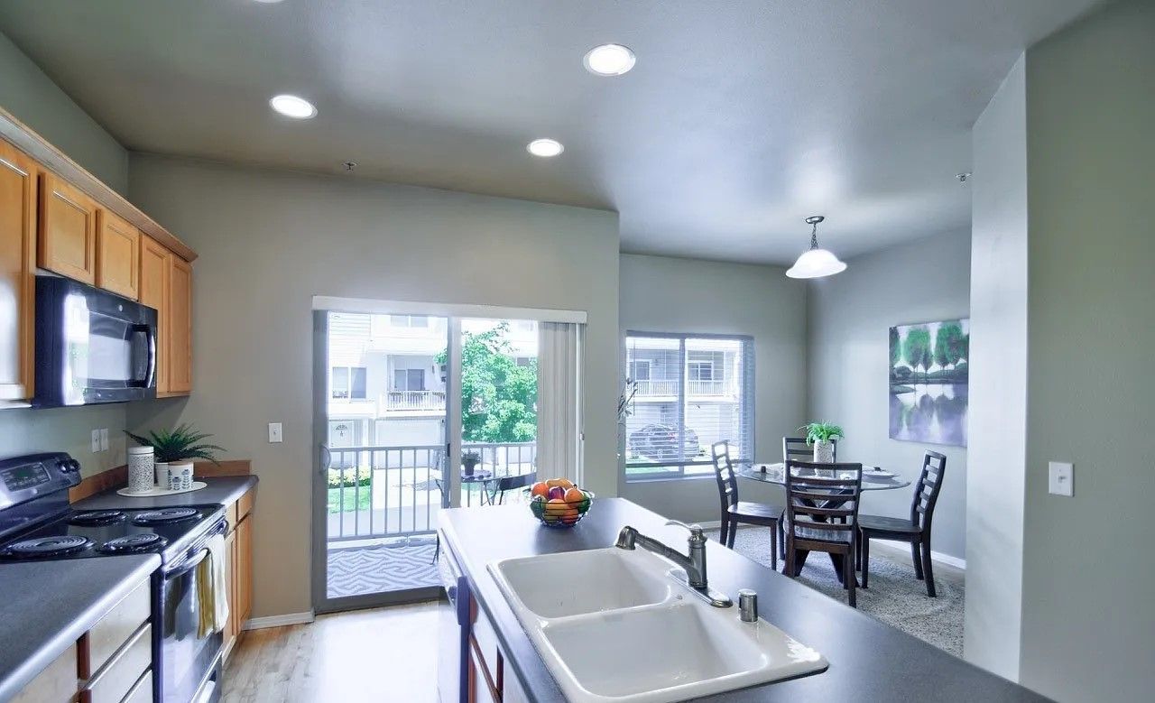 Kitchen with island, sliding glass door to balcony, and dining area with round table and chairs.